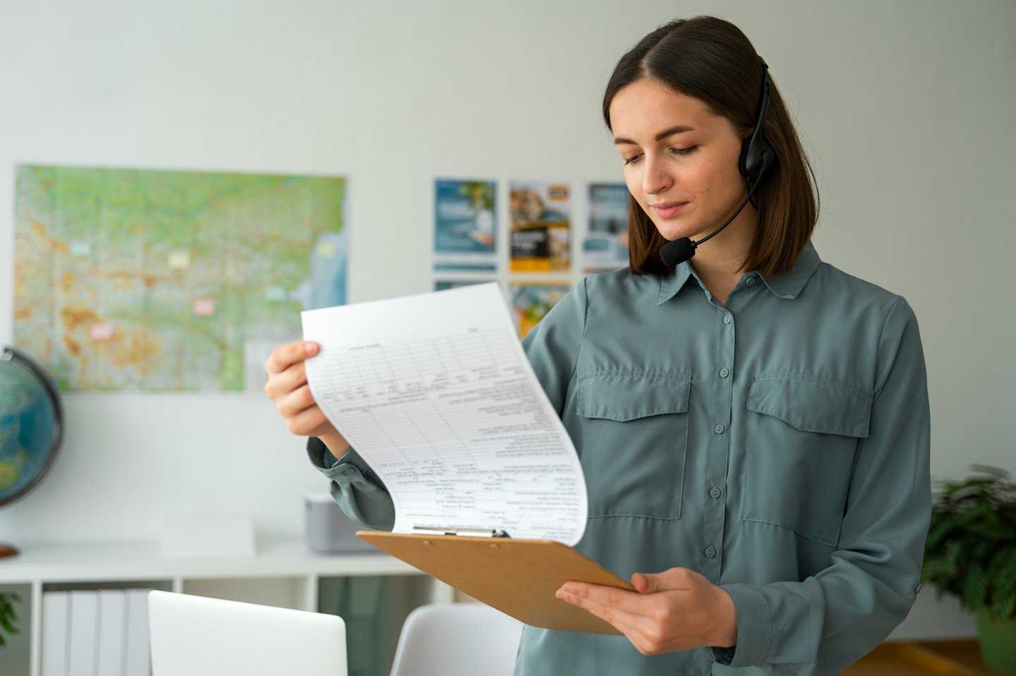 Woman in headset reads from clipboard in an office.